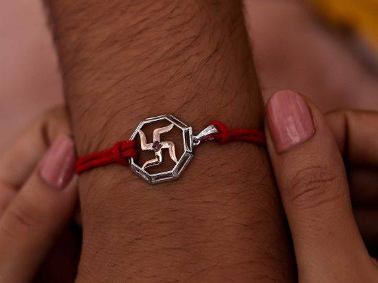 Swastika Silver Rakhi Pendant on wrist